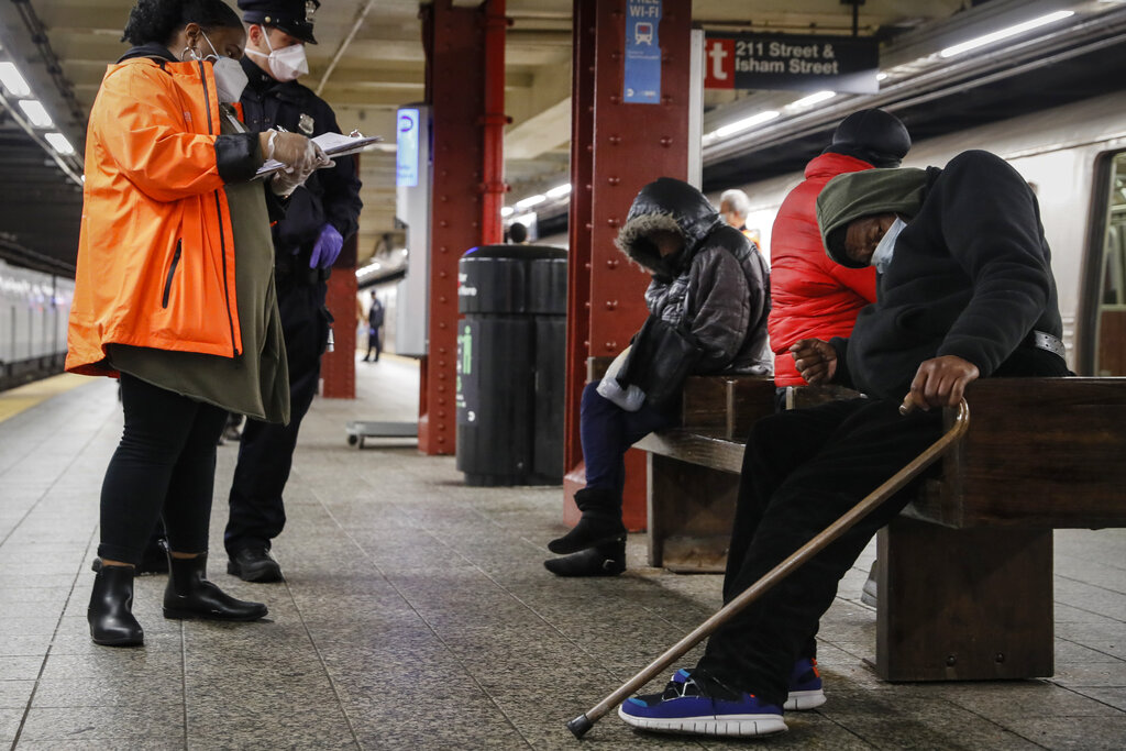 A homeless outreach worker and New York police officer assist passengers found sleeping on subway cars at the 207th Street A train station, April 30, 2020, at New York.