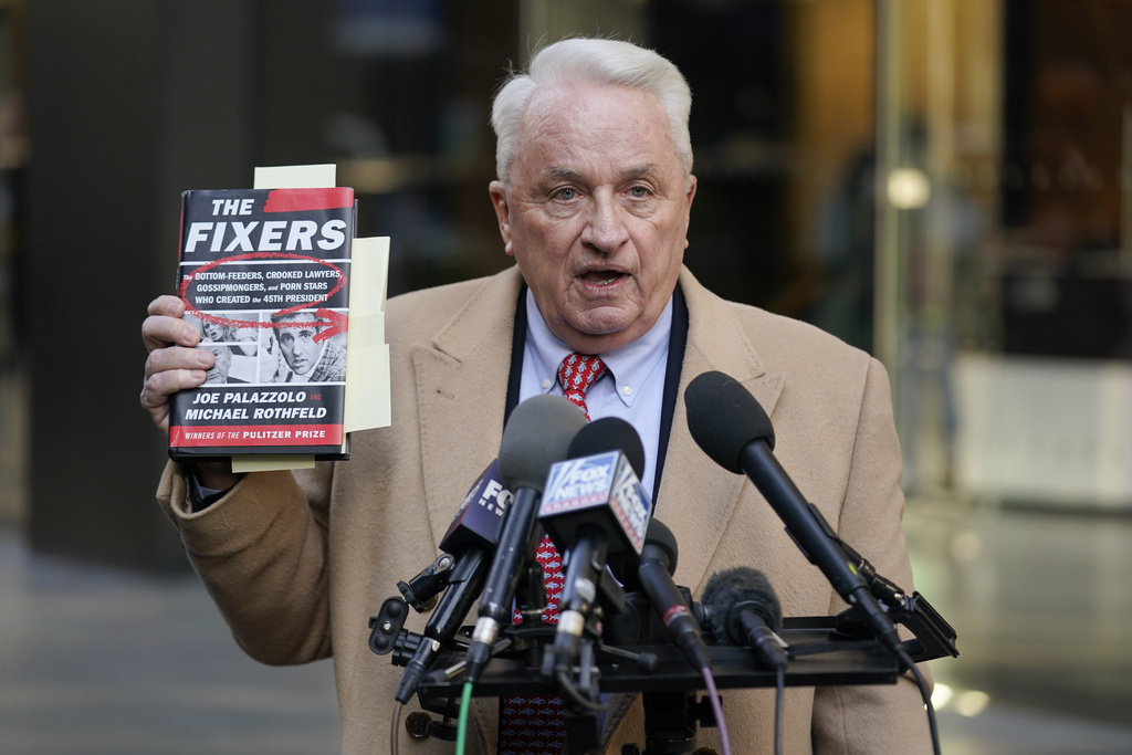 Attorney Bob Costello holds up a book while talking to reporters after testifying before a grand jury investigating Donald Trump in New York, Monday, March 20, 2023.