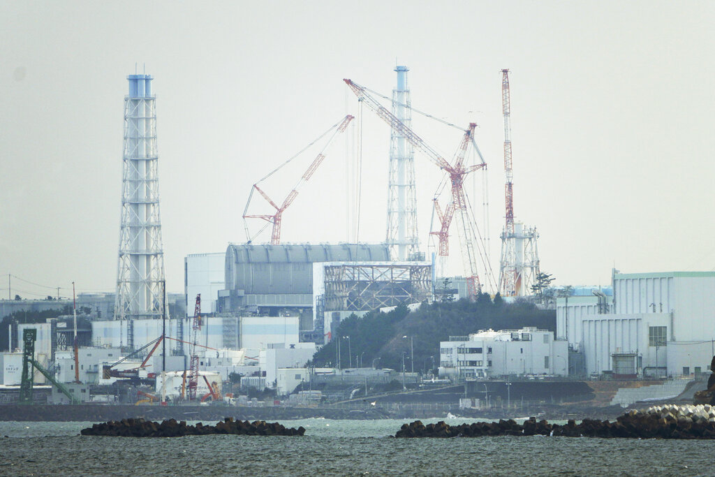 FILE - The Fukushima Daiichi nuclear power plant sits in coastal towns of both Okuma and Futaba, as seen from the Ukedo fishing port in Namie town, northeastern Japan, Wednesday, March 2, 2022. Japanese nuclear regulators on Monday, Feb. 13, 2023 approved contentious safety evaluation changes and draft legislation to allow aging reactors to operate longer, in a rare split decision in which one of the five commissioners dissented. (