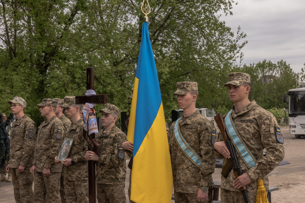 KYIV, UKRAINE - MAY 17: Military members hold Ukrainian flag and a portrait of Oleksandr Khmil, a Ukrainian hockey player and serviceman, who was killed fighting Russian troops near Bakhmut, Donetsk region, during his funeral on May 17, 2023 in Kyiv, Ukraine. The battle in Bakhmut, in the eastern Donbas region, has been one of the most sustained and deadly fights in the war. In recent days Ukraine has claimed to have retaken 20-square-kilometers in northern and southern parts of the city. (Photo by