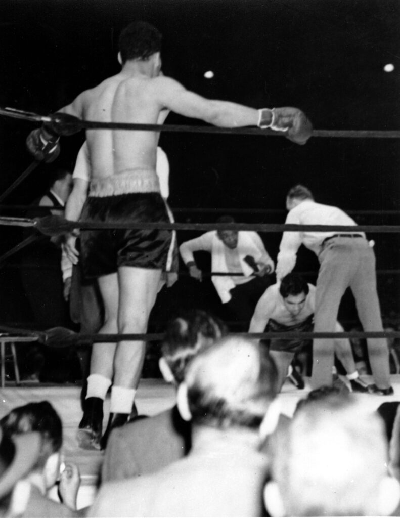 Max Schmeling, toppled by blows from Joe Louis, is being helped by Referee Arthur Donovan at New York on June 22, 1938.