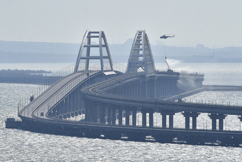 A helicopter drops water to stop a fire on the bridge connecting the Russian mainland and the Crimean peninsula over the Kerch Strait, October 8, 2022.