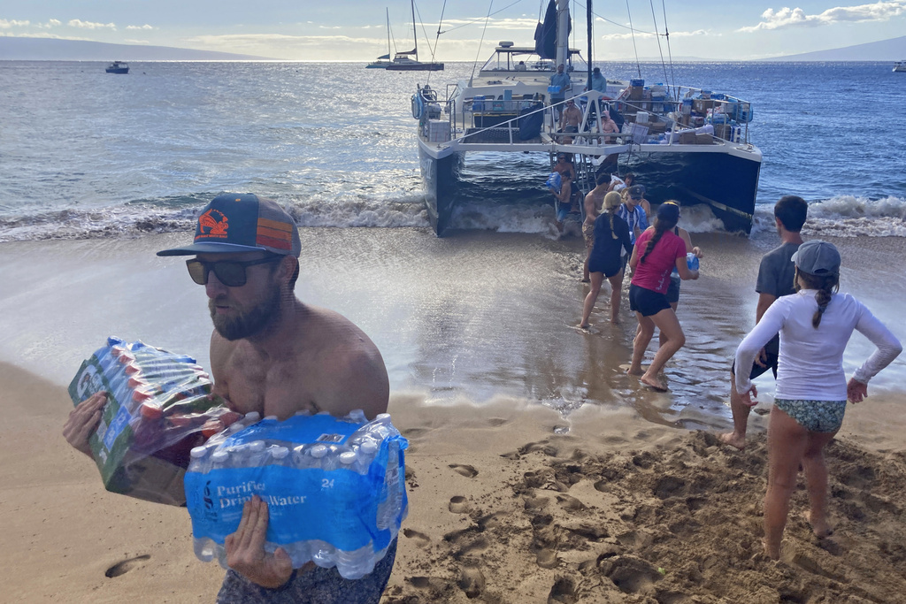 A group of volunteers unloads donations from a boat on Kaanapali Beach on Saturday, August 12, 2023.