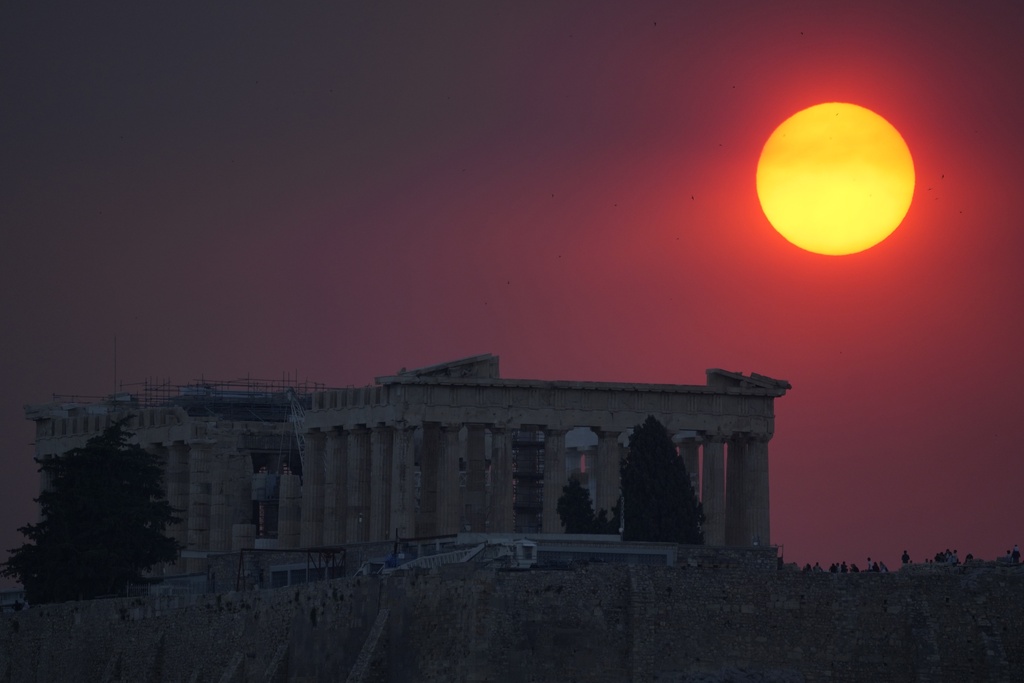 Smoke from a wildfire in the outskirts of the Greek capital covers the sun as it sets over the Parthenon temple atop of the ancient Acropolis ancient in Athens, Tuesday, Aug. 22, 2023.