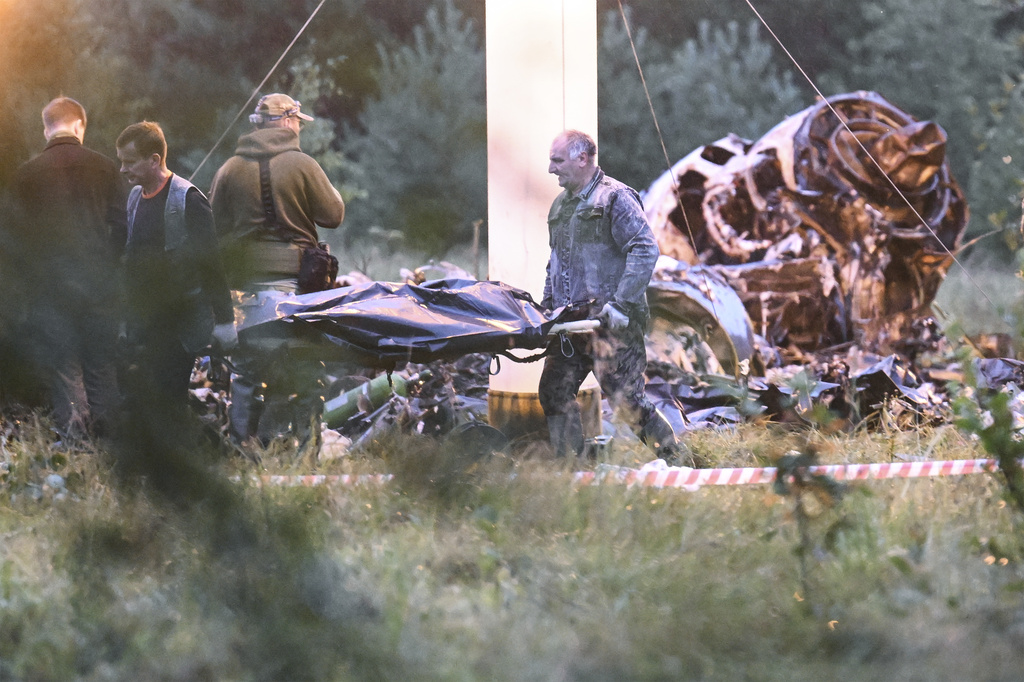 People carry a body bag away from the wreckage of a crashed private jet, near the village of Kuzhenkino, Tver region, Russia, Thursday, Aug. 24, 2023. Russian mercenary leader Yevgeny Prigozhin, the founder of the Wagner Group, reportedly died when a private jet he was said to be on crashed on Aug. 23, 2023, killing all 10 people on board.