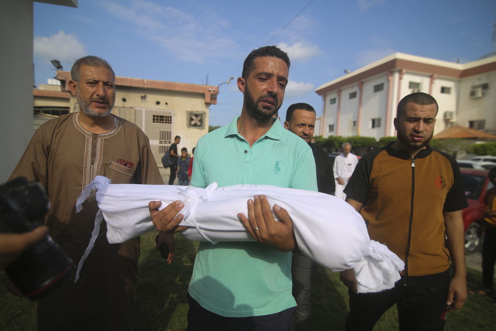 A relative carries the body of Amir Ganan, who was killed in an Israeli airstrike, during his funeral in Khan Younis, Gaza Strip, Tuesday, Oct. 10, 2023.