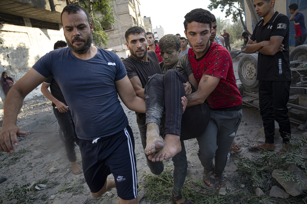 Palestinians carry a person wounded in Israeli airstrikes in Khan Younis, Gaza Strip, Monday, Oct. 16, 2023. (