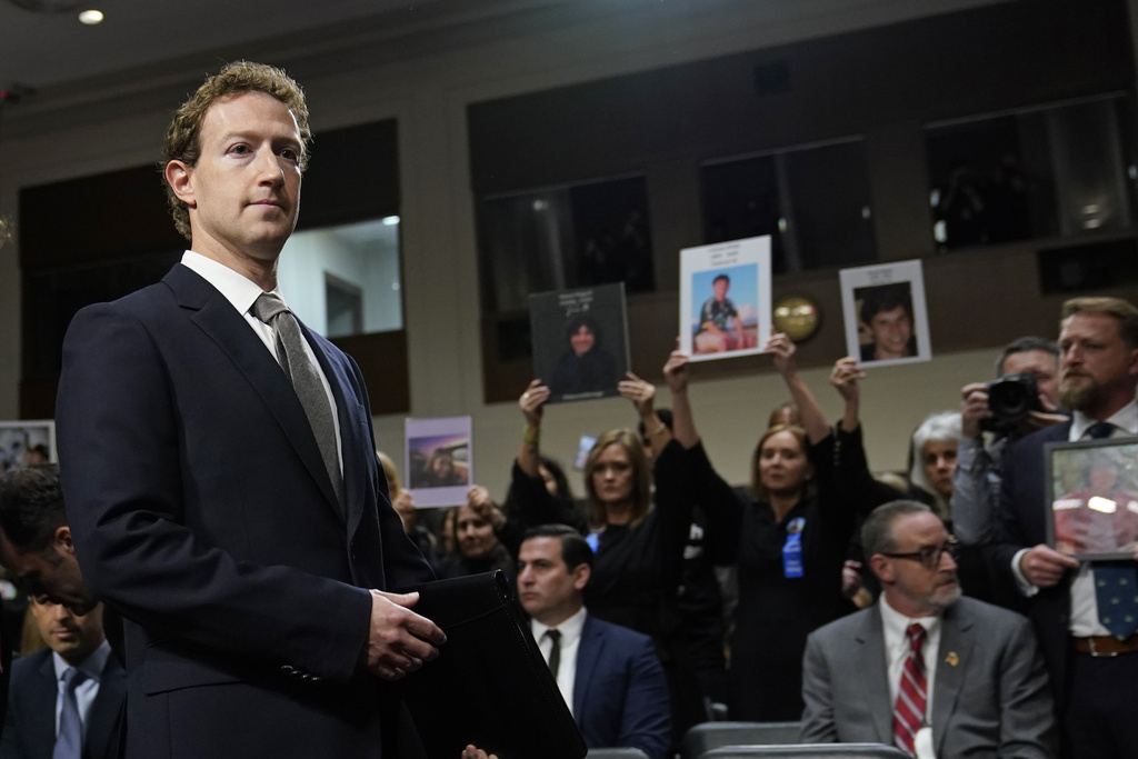 People hold pictures of their loved ones as Mark Zuckerberg arrives at a Senate Judiciary Committee hearing at Washington, D.C., on January 31, 2024.