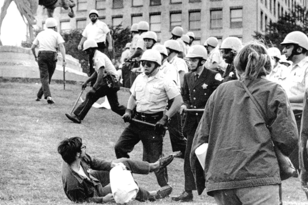 FILE - In this Aug. 26, 1968 file photo, Chicago police officers wielding nightsticks confront a demonstrator on the ground in Grant Park after protesters against the Vietnam War climbed on the statue of Civil War Gen. John Logan. It was one of many protests during the tumultuous 1968 Democratic National Convention.