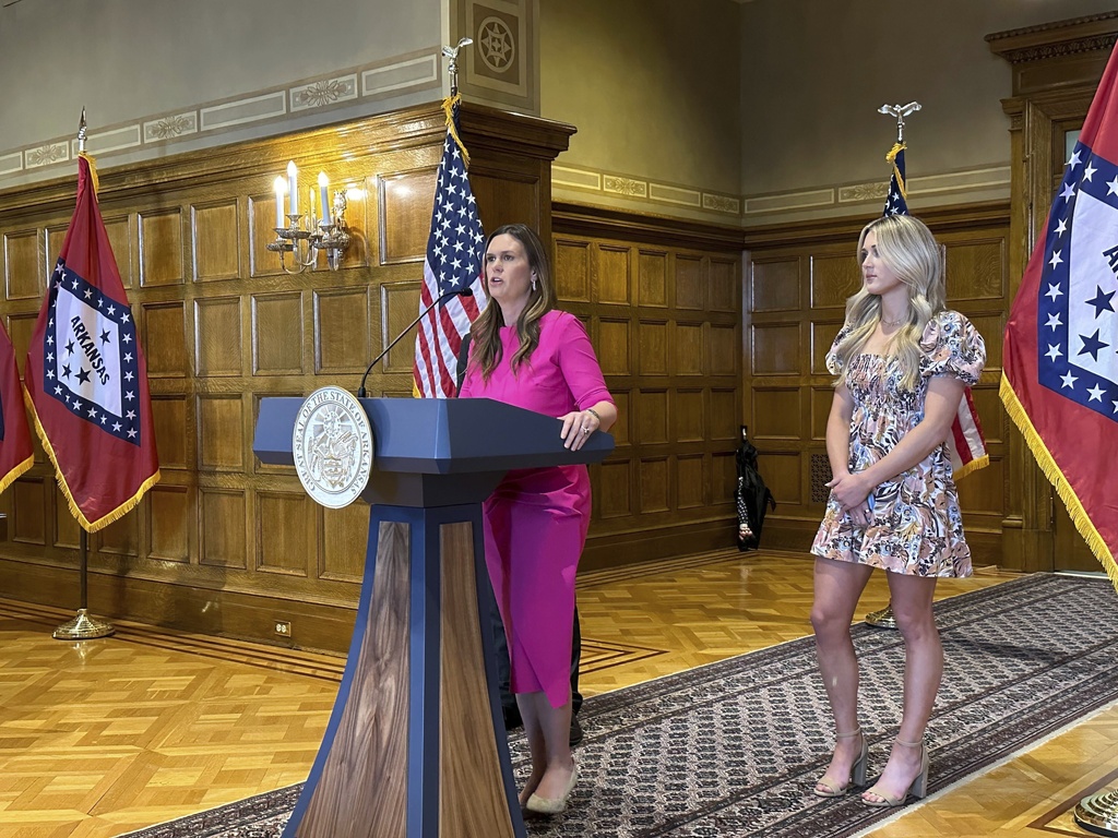 The governor of Arkansas, Sarah Huckabee Sanders, speaks at a news conference next to former Kentucky swimmer Riley Gaines before signing an executive order stating that Arkansas won't comply with new federal regulations intended to protect the rights of transgender students.