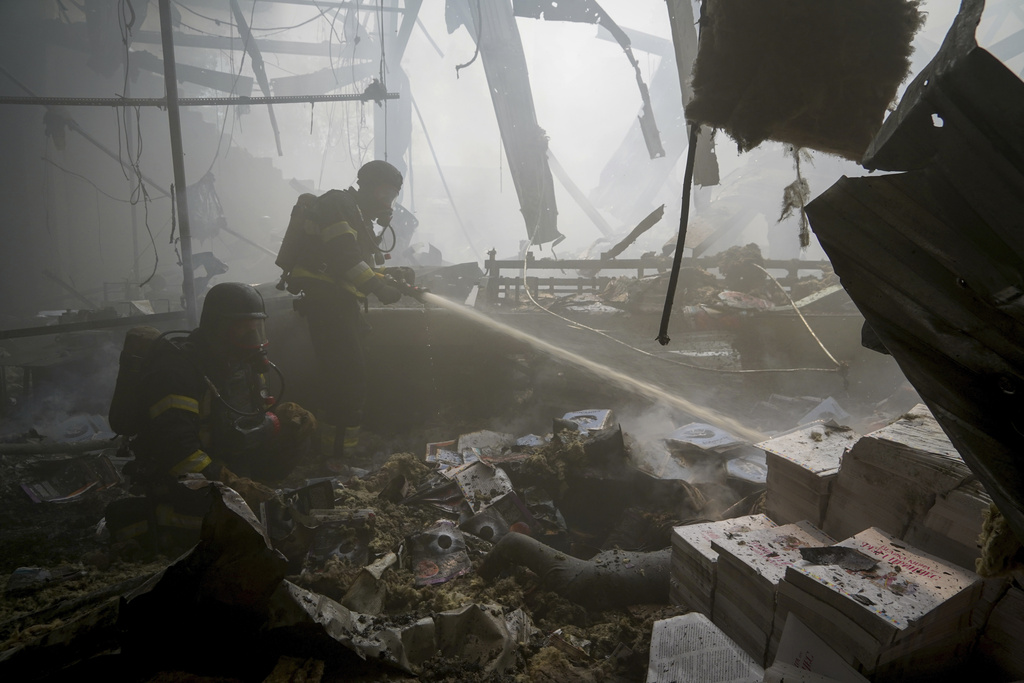 Firefighters hose down a fire as a lifeless body lies under the rubble after a Russian missile hit a large printing house in Kharkiv, Ukraine, Thursday, May 23, 2024. Russian missiles slammed into Ukraine’s second-largest city in the northeast of the country and killed at least seven civilians early Thursday, officials said, as Kyiv’s army labored to hold off an intense cross-border offensive by the Kremlin’s larger and better-equipped forces.