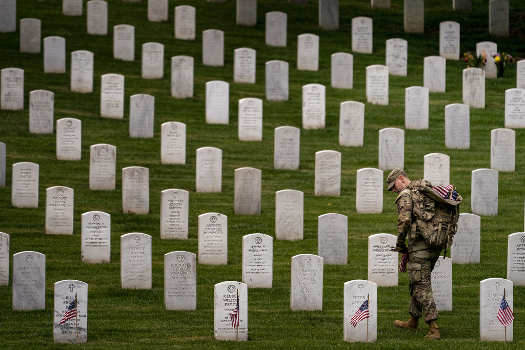 A member of the 3rd U.S. Infantry Regiment also known as The Old Guard, places flags in front of each headstone at Arlington National Cemetery.