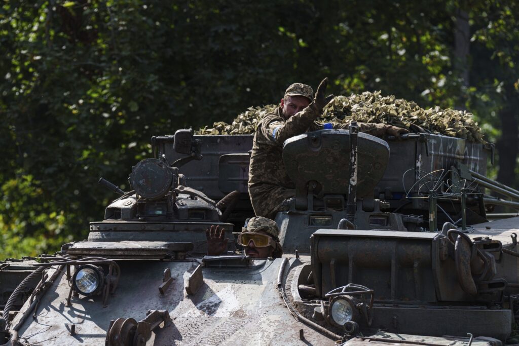 Ukrainian servicemen ride atop on armoured vehicle at the Russian-Ukrainian border in Sumy region, Ukraine, Wednesday, Aug. 14, 2024.