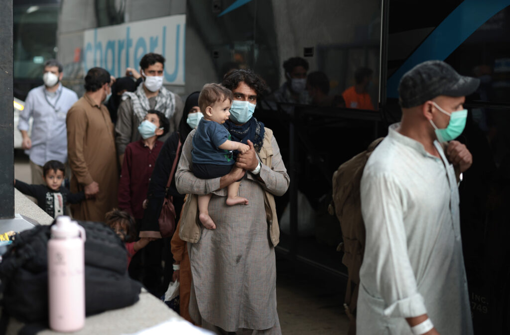 DULLES, VIRGINIA - AUGUST 31: Refugees board a bus at Dulles International Airport  that will take them to a refugee processing center after being evacuated from Kabul following the Taliban takeover of Afghanistan on August 31, 2021 in Dulles, Virginia. The Department of Defense announced yesterday that the U.S. military had completed its withdrawal from Afghanistan, ending 20 years of war. (Photo by Anna Moneymaker/Getty Images)