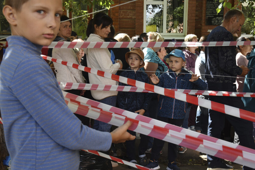 People evacuated from fighting between Russian and Ukrainian forces queue to receive humanitarian aid at a distribution center in Kursk, Russia, Monday, Aug. 12, 2024.