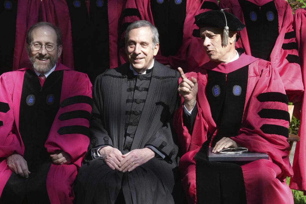 Harvard University Provost Alan Garber, left, Harvard President Lawrence Bacow, center, and actor Tom Hanks, right, speak while sitting for a photograph before joining a procession though Harvard Yard at the start of Harvard University commencement exercises, Thursday, May 25, 2023, on the schools campus, in Cambridge, Mass. (