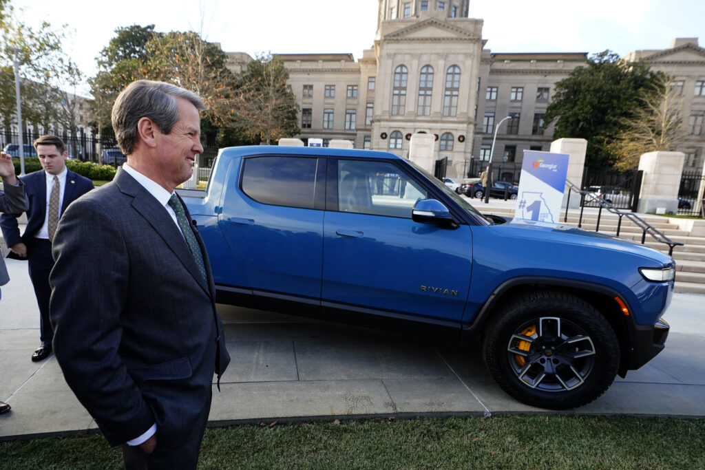 Governor Kemp of Georgia stands next to a Rivian electric truck during a ceremony to announce that the electric truck maker plans to build a battery and assembly plant east of Atlanta.