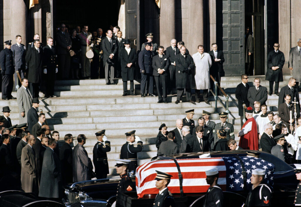 FILE - A general view outside St. Matthew's Cathedral in Washington, D.C., during President John F. Kennedy's funeral, with flag-draped coffin in the foreground, Nov. 25, 1963. The president's brothers can be seen behind the casket. At left is Sen. Edward M. Kennedy (D-Mass.), and at right entering limousine is Attorney General Robert F. Kennedy.