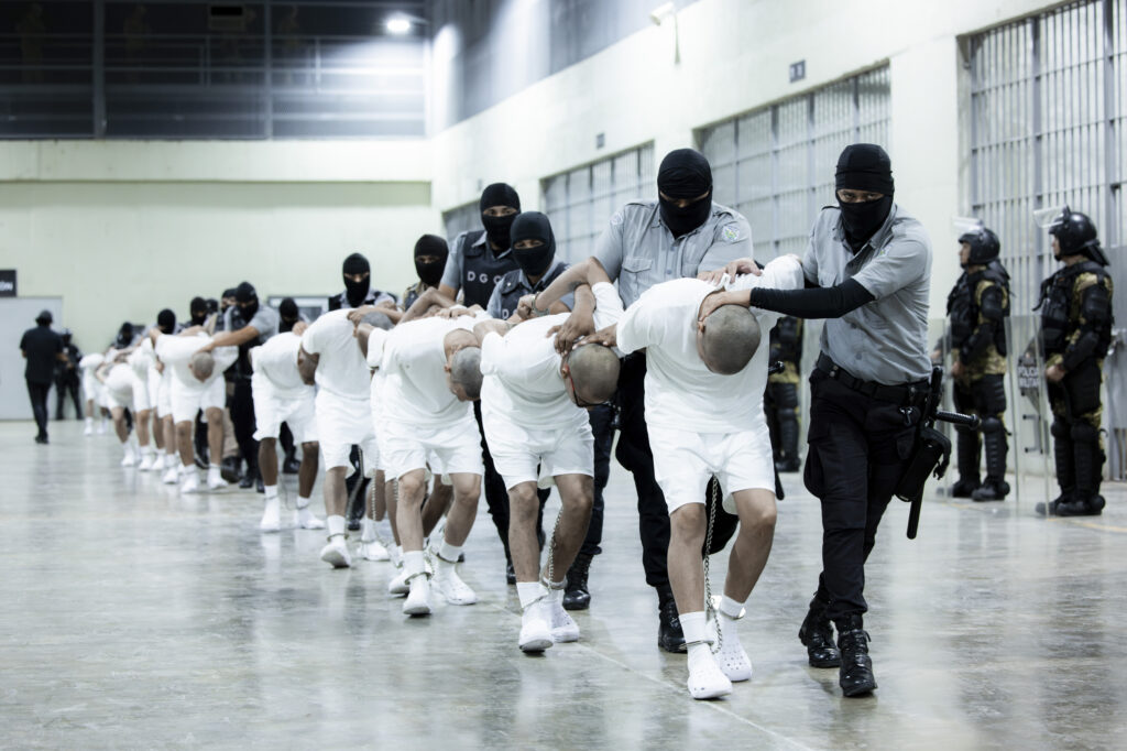 In this photo provided by El Salvador's presidential press office, prison guards transfer deportees from the U.S., alleged to be Venezuelan gang members, to the Terrorism Confinement Center in Tecoluca, El Salvador, Sunday, March 16, 2025.