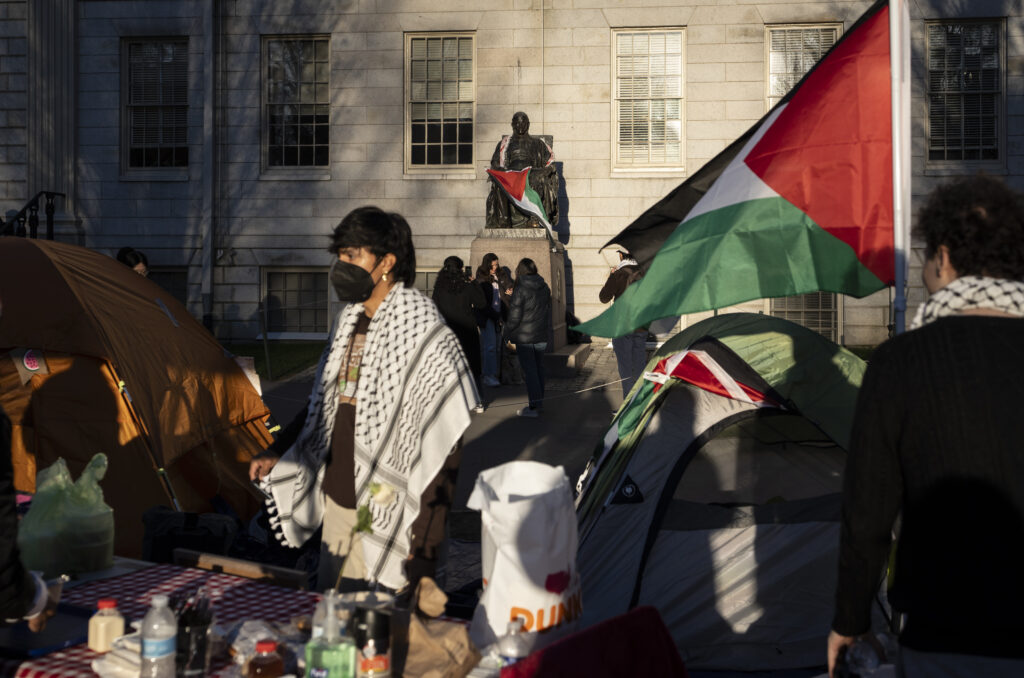 FILE - A student protester stands in front of the statue of John Harvard, the first major benefactor of Harvard College, draped in the Palestinian flag, at an encampment of students protesting against the war in Gaza, at Harvard University in Cambridge, Mass., April 25, 2024.