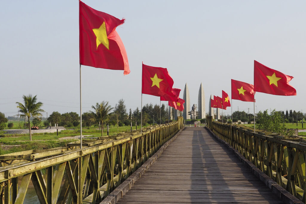 Vietnamese flags fly on the Hien Luong Bridge, with a memorial in the distance, at the former border between North and South Vietnam, Quang Tri province, Feb. 22, 2024.