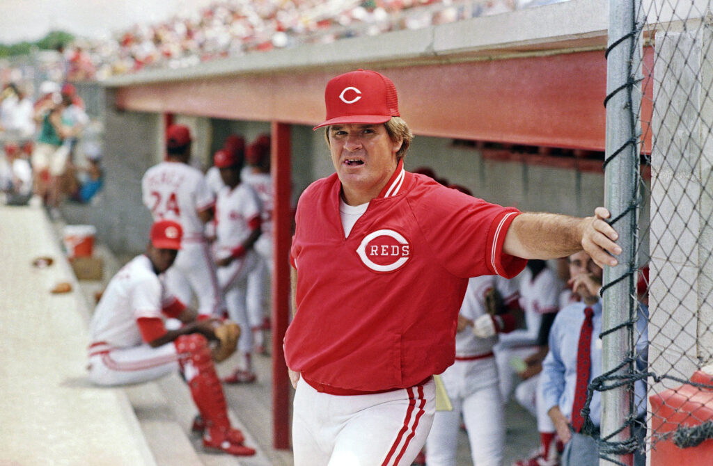 Cincinnati Reds' manager Pete Rose leans against the dugout fence before the start of a baseball game. March 22, 1989.