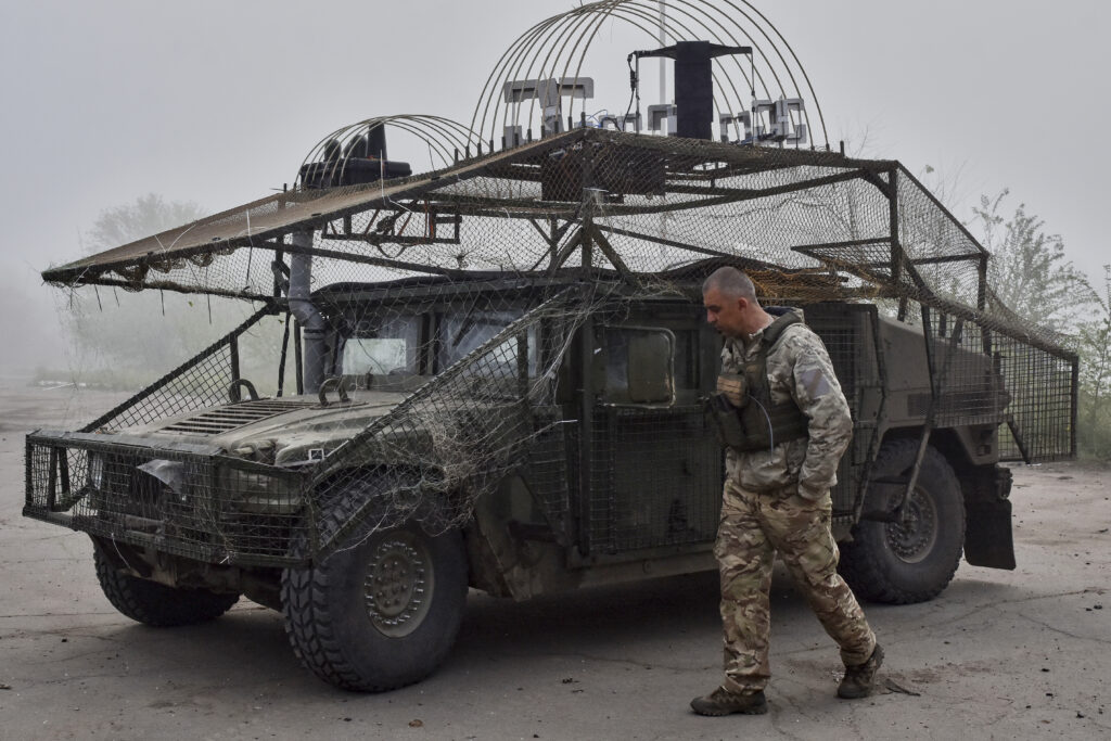In this photo provided by Ukraine's 65th Mechanized Brigade press service, a Ukrainian soldier passes by an armoured Hummer vehicle equipped with an anti-drone net on the frontline in the Zaporizhzhia region, Ukraine, Monday, May 5, 2025.