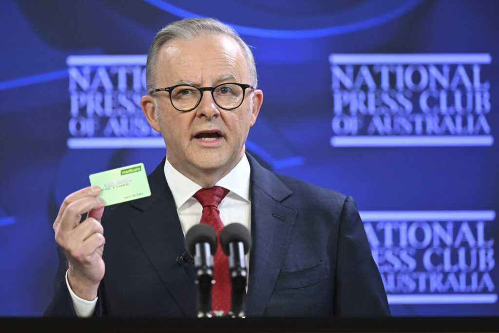 Australian Prime Minister Anthony Albanese holds a Medicare card as he addresses the National Press Club in Canberra, Wednesday, April 30, 2025. (Lukas Coch/AAP Image via AP)
