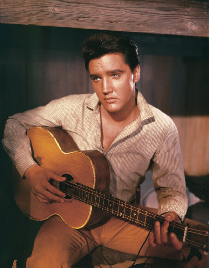 A portrait of American singer and actor Elvis Presley holding an acoustic guitar circa 1956. (Photo by
