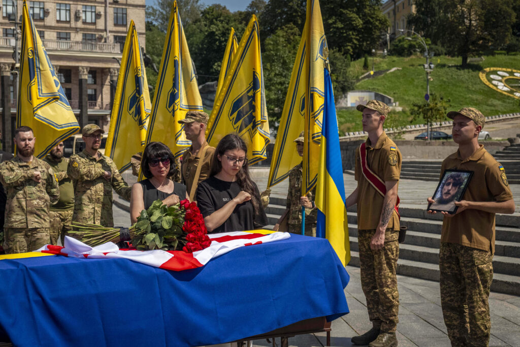 Relatives and soldiers of the Azov Regiment pay last respect near the coffin of their comrade, Georgian volunteer Mykhailo Kovaliv, during a farewell ceremony on Independence Square in Kyiv, Ukraine, Saturday, Aug. 9, 2025.