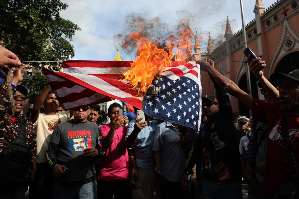 CARACAS, VENEZUELA - JANUARY 03: Supporters of Nicolas Maduro burn a United States flag during a gathering near Miraflores palace after explosions and low-flying aircraft were heard in the early hours on January 03, 2026 in Caracas, Venezuela. According to some reports, explosions were heard in Caracas and other cities near airports and military bases around 2 am. US President Donald Trump later announce that his country's military had launched a "large-scale" attack on Venezuela and captured its President Nicolas Maduro and his wife. (Photo by Jesus Vargas/Getty Images)